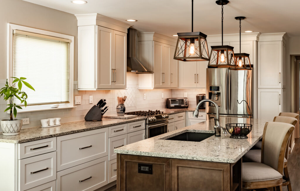A newly renovated Mediterranean Kitchen with coordinating white cabinets and a dark wood island, along with rustic edison lights